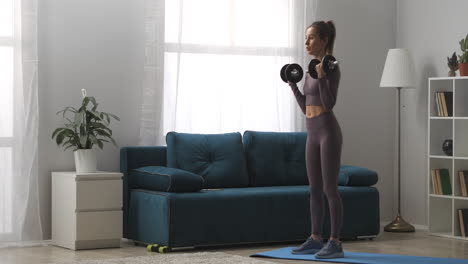 daily-home-workout-young-athletic-woman-is-training-with-dumbbells-in-living-room-at-daytime-full-length-portrait-of-sportswoman-in-modern-interior-healthy-lifestyle